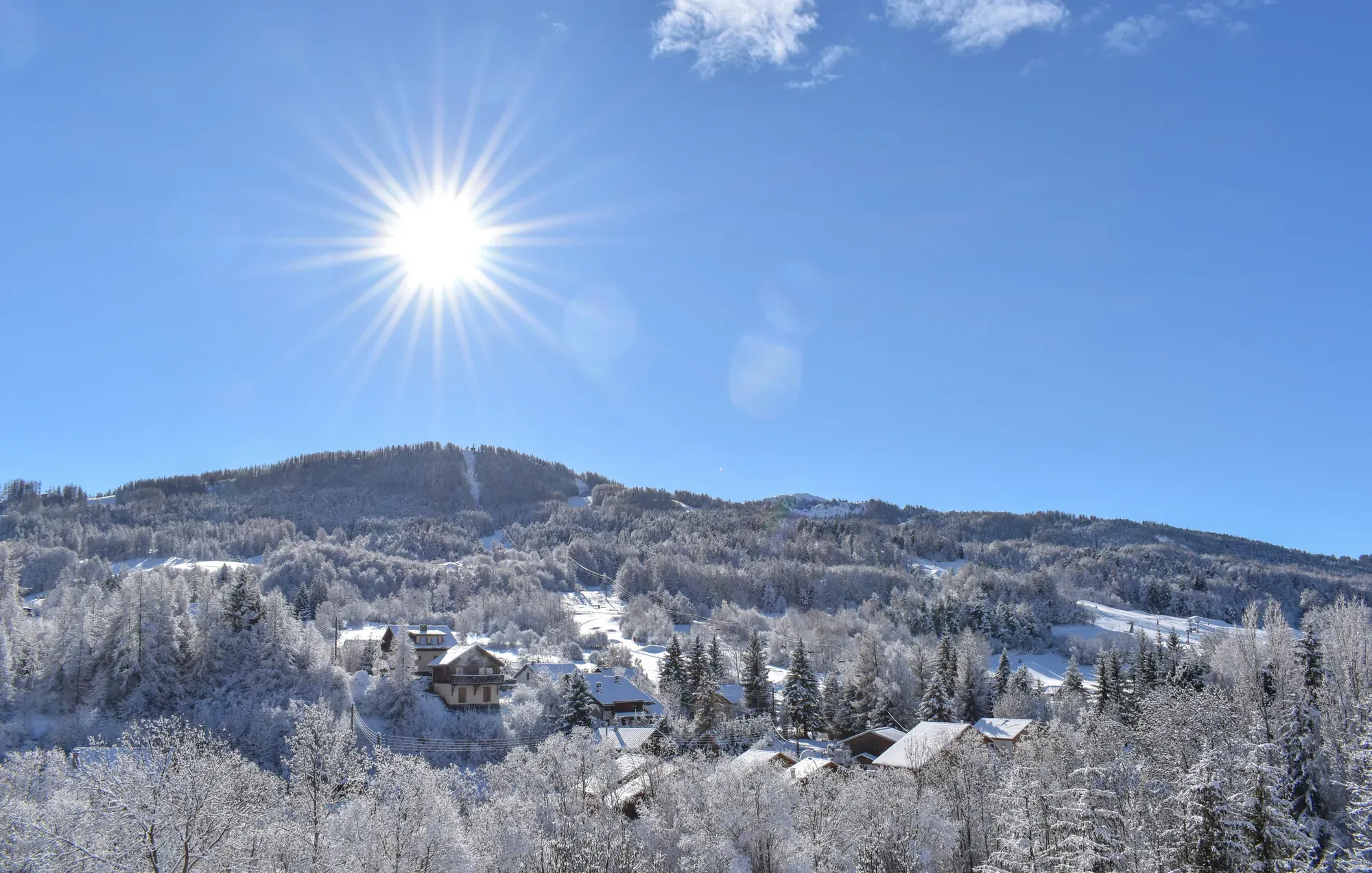 Le domaine skiable d'Ancelle sous le givre, soleil au-dessus des mélèzes et chalets au départ des pistes