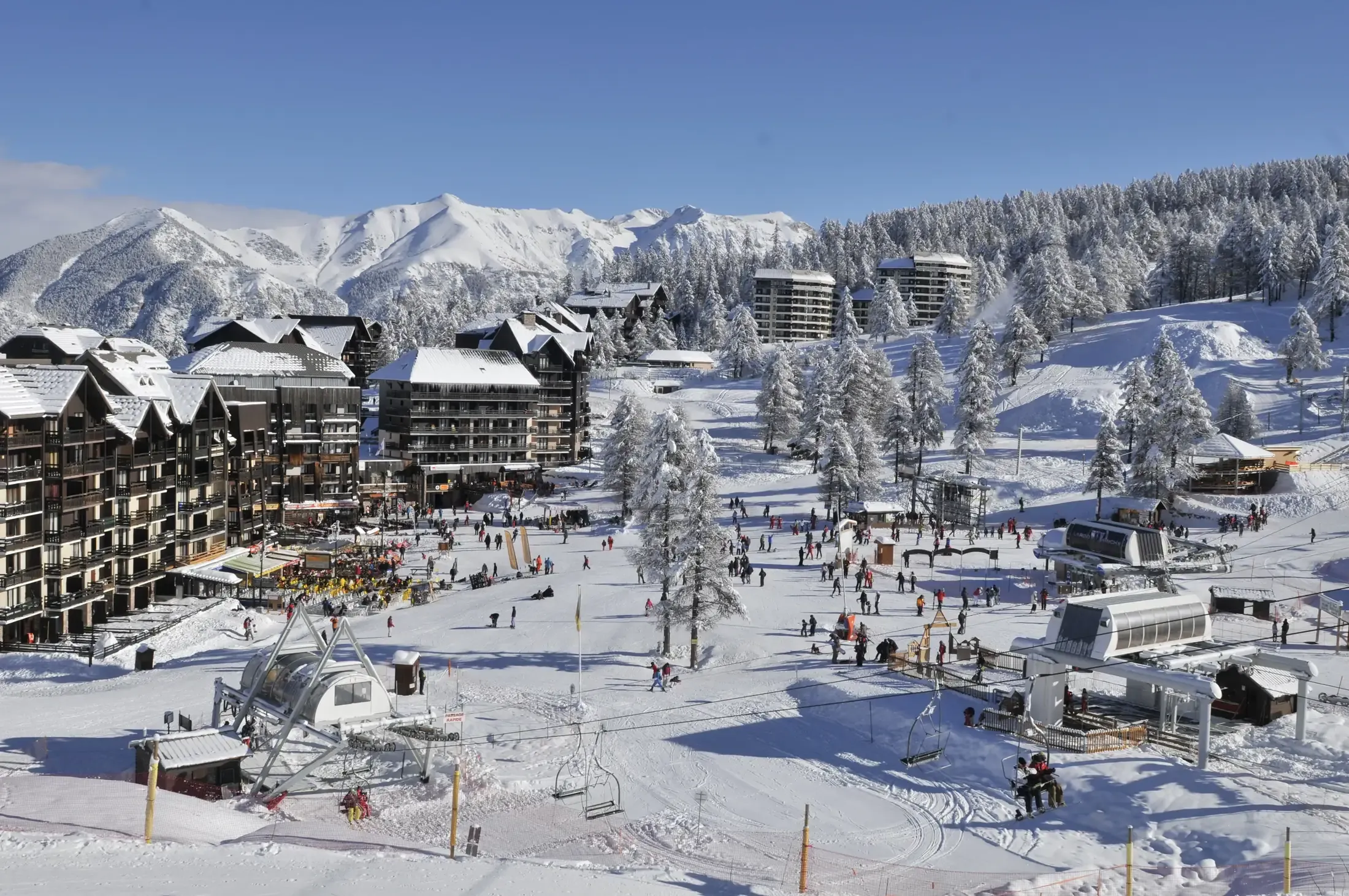 Le front de neige d'Ancelle en pleine saison : skieurs, terrasses et immeubles au départ des pistes