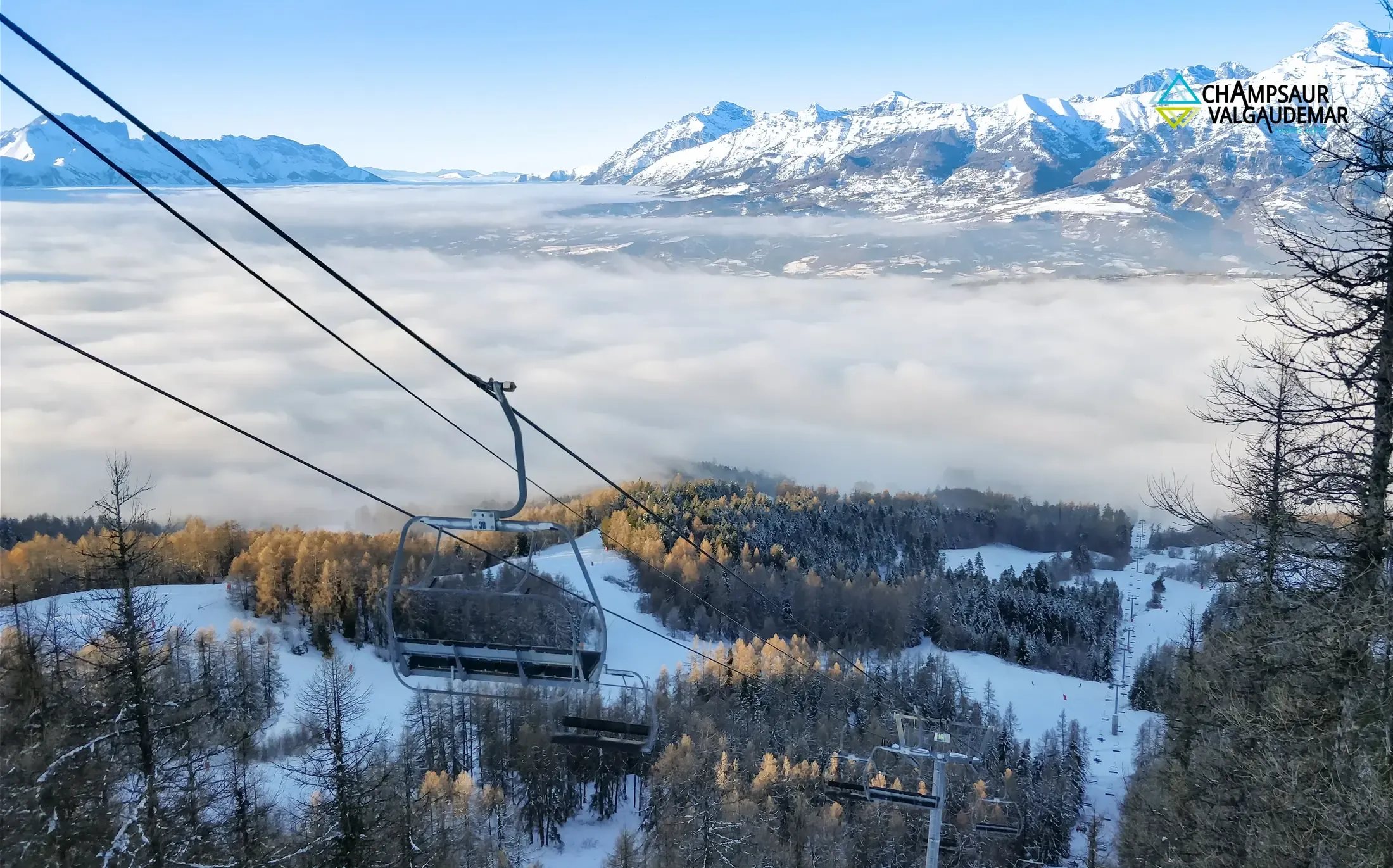 Télésiège au-dessus d'une mer de nuages à Ancelle, mélèzes dorés et sommets enneigés du Champsaur